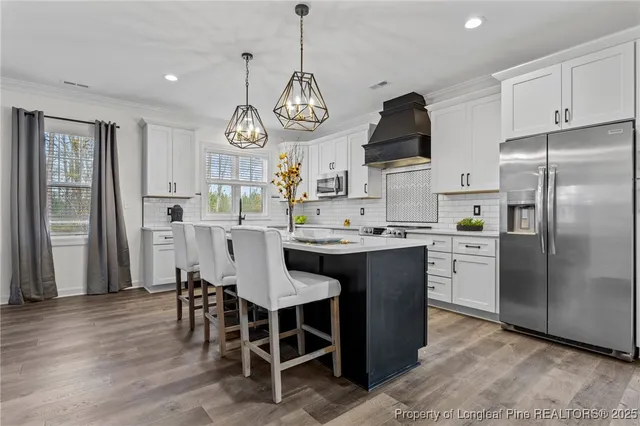 a large kitchen with a dining table a sink stainless steel appliances and cabinets