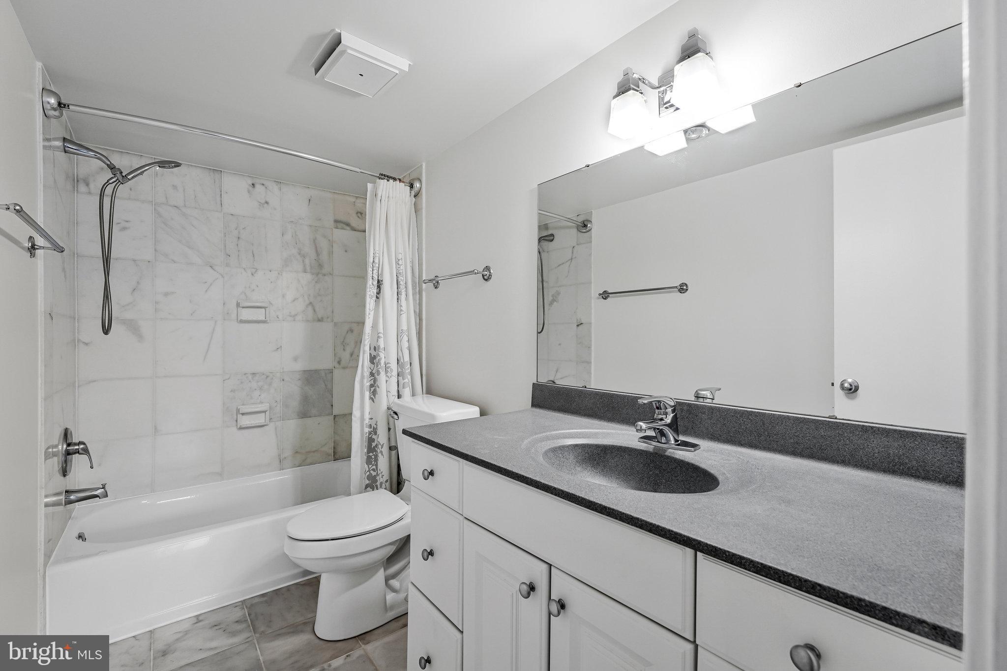 1800 Old Meadow Road, Unit 302 McLean, VA 22102 - Photo 18 of 35 a bathroom with a granite countertop sink a toilet a mirror a bathtub and shower
