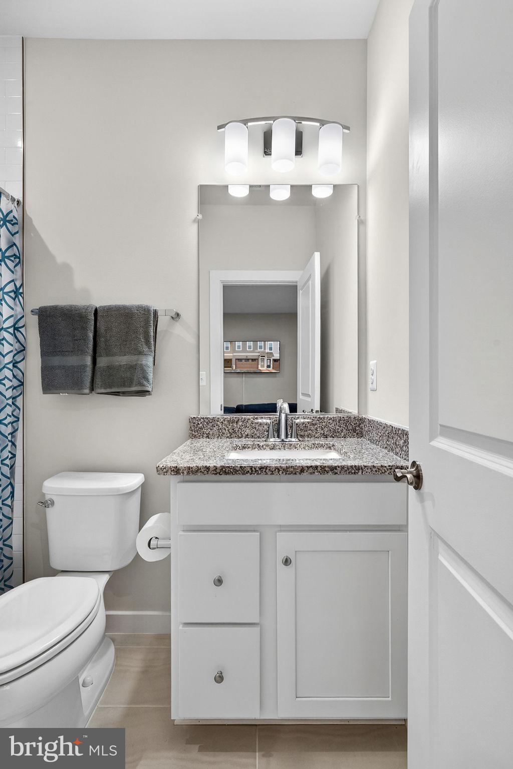 18245 Moss Garden Road Dumfries, VA 22026 - Photo 33 of 71 a bathroom with a granite countertop toilet sink and mirror