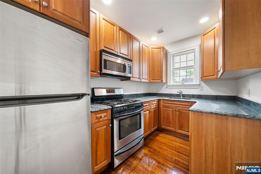 180 Edgewater Road, Unit 1A Cliffside Park, NJ 07010 - Photo 13 of 30 a kitchen with stainless steel appliances granite countertop a refrigerator a sink a stove top oven and a dishwasher