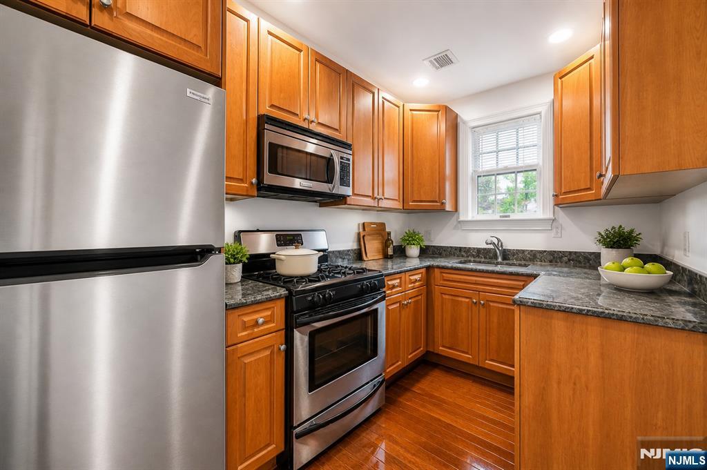 180 Edgewater Road, Unit 1A Cliffside Park, NJ 07010 - Photo 3 of 30 a kitchen with stainless steel appliances granite countertop a refrigerator a sink a stove top oven and a dishwasher