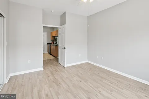 a view of a hallway with wooden floor and a kitchen