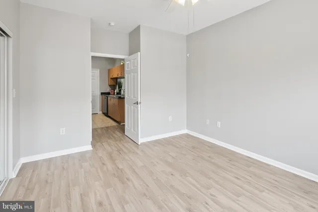a view of a hallway with wooden floor and a kitchen