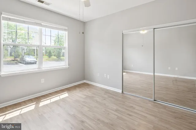 a view of an empty room with window and wooden floor