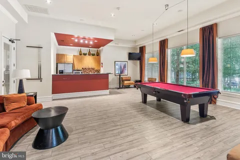 a room with furniture pool table wooden floor and windows