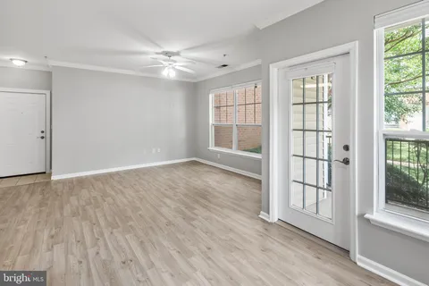 an empty room with wooden floor and windows