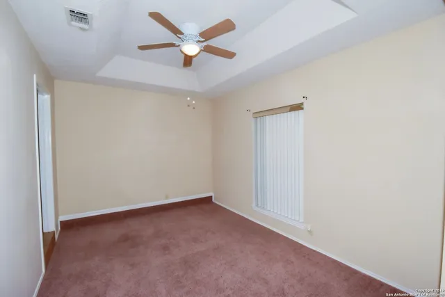 an empty room with a ceiling fan and a window