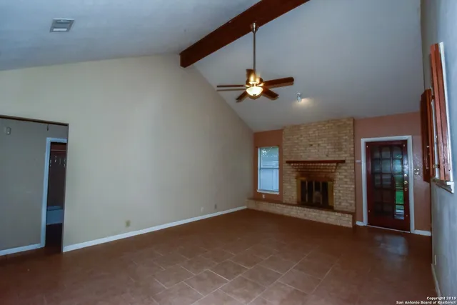 an empty room with chandelier fan and windows
