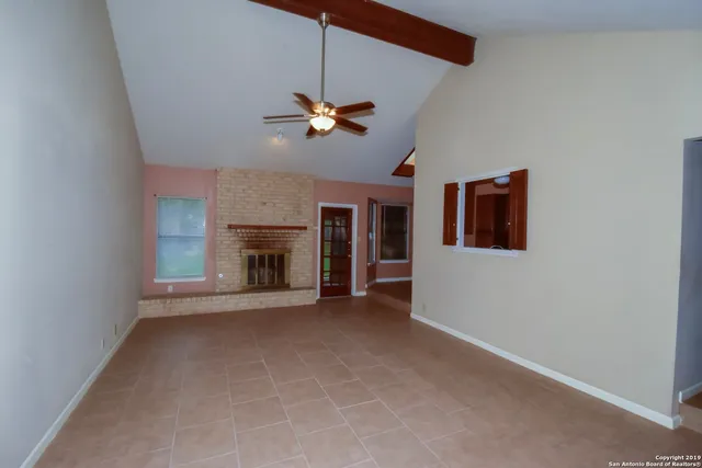 a view of a livingroom with a ceiling fan fireplace and a window