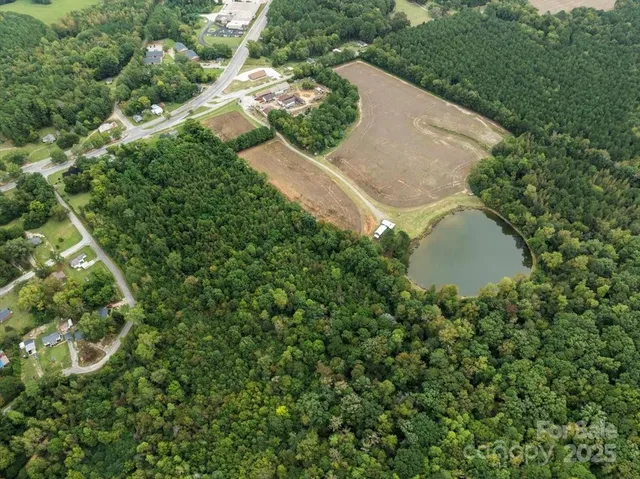 an aerial view of residential house with outdoor space and trees all around