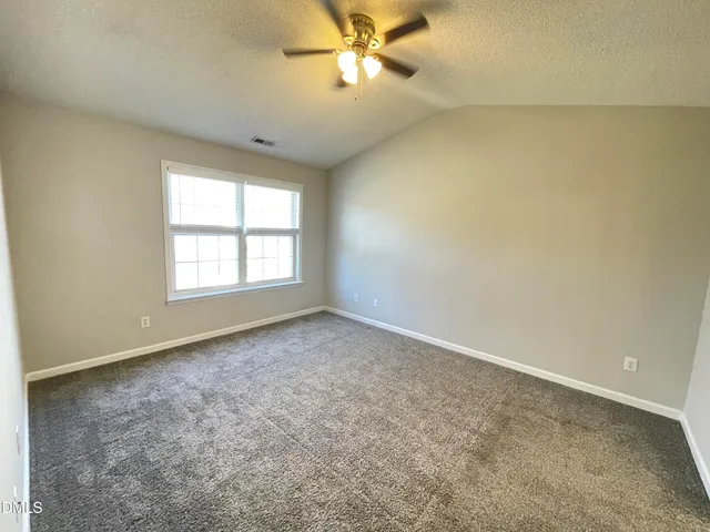 an empty room with a chandelier fan and windows