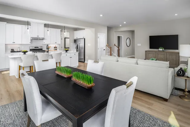 a kitchen that has a sink a stove and white cabinets with wooden floor