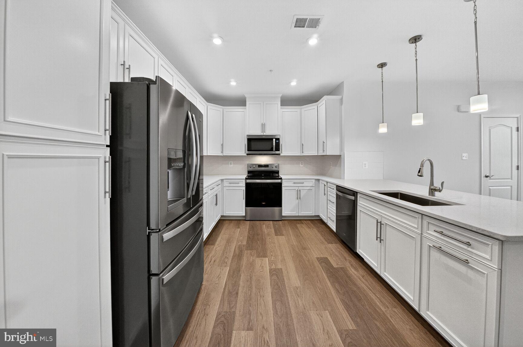 9990 A Justify Run Laurel, MD 20723 - Photo 3 of 28 a kitchen with kitchen island a counter top space a sink and stainless steel appliances