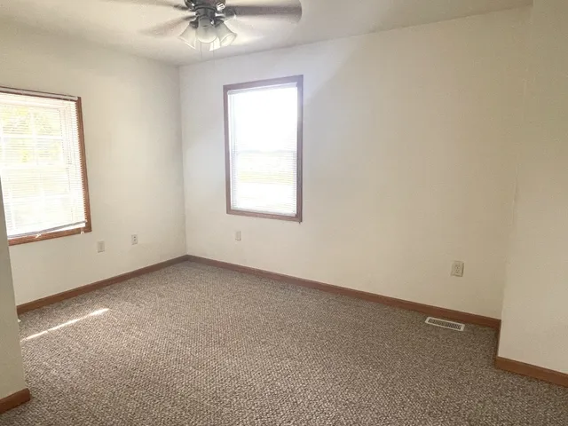 an empty room with a window and a ceiling fan