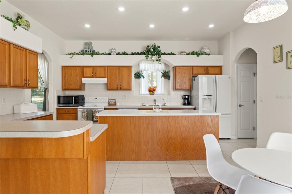 11405 Warm Wind Way Weeki Wachee, FL 34613 - Photo 23 of 46 a large kitchen with stainless steel appliances kitchen island granite countertop a refrigerator and a stove top oven
