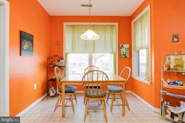 a kitchen with a refrigerator a stove a dining table and chairs with wooden floor