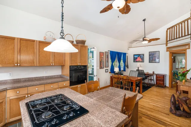 a kitchen with stainless steel appliances a stove a sink a dining table and chairs with wooden floor