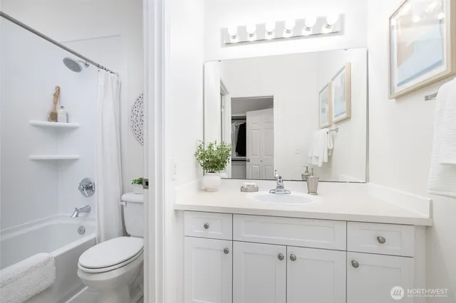 a bathroom with a bathtub shower sink vanity mirror and toilet