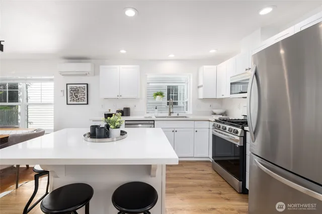 a kitchen with a refrigerator a stove a sink and white cabinets with wooden floor