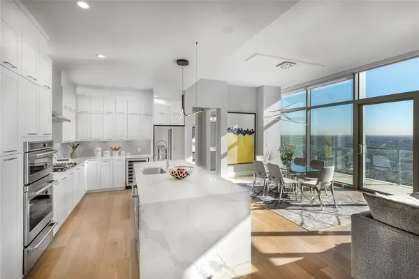a view of a kitchen with kitchen island a large window cabinets a sink and stainless steel appliances