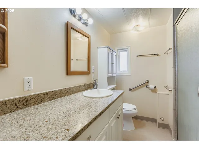 a bathroom with a granite countertop sink toilet and mirror