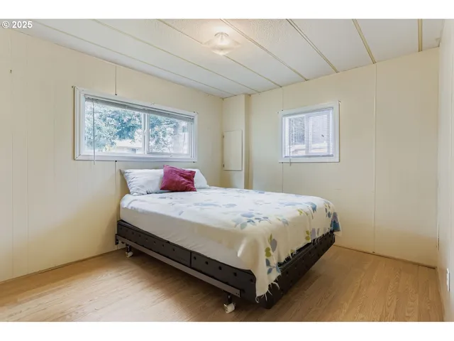 a bedroom with a bed painting on the wall and a window