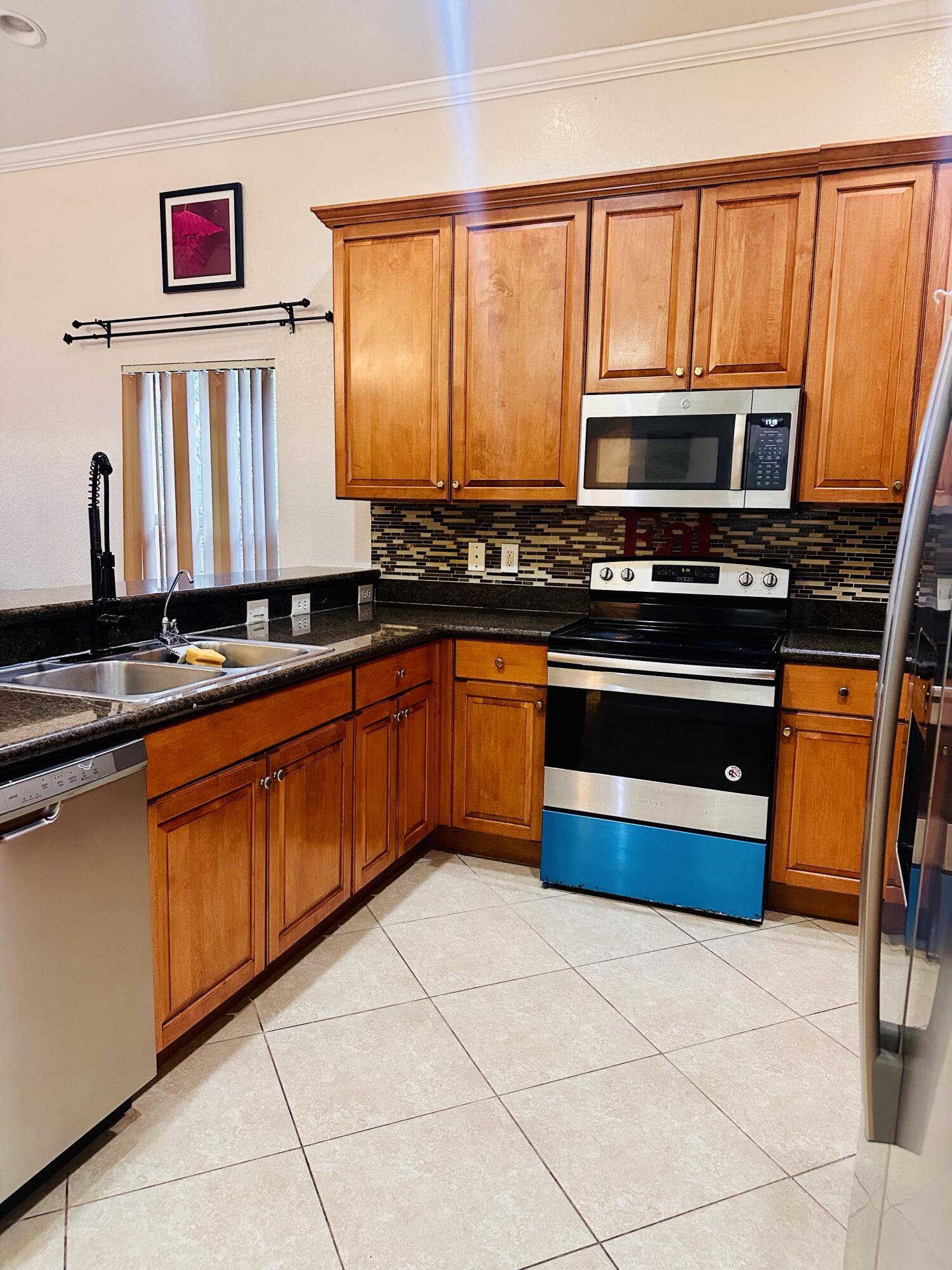 5200 Rising Comet Lane Greenacres, FL 33463 - Photo 13 of 50 a kitchen with stainless steel appliances a stove a sink and a microwave