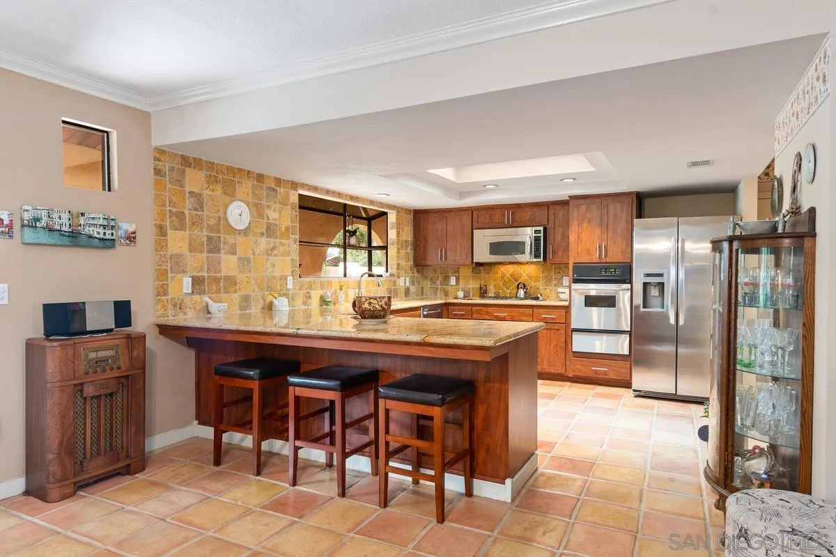 13767 Proctor Valley Road Jamul, CA 91935 - Photo 13 of 50 a kitchen with stainless steel appliances granite countertop a table chairs sink refrigerator and cabinets