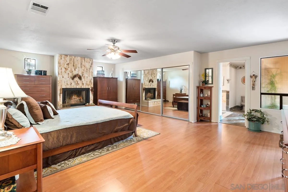 13767 Proctor Valley Road Jamul, CA 91935 - Photo 19 of 50 a spacious bedroom with a bed and wooden floor