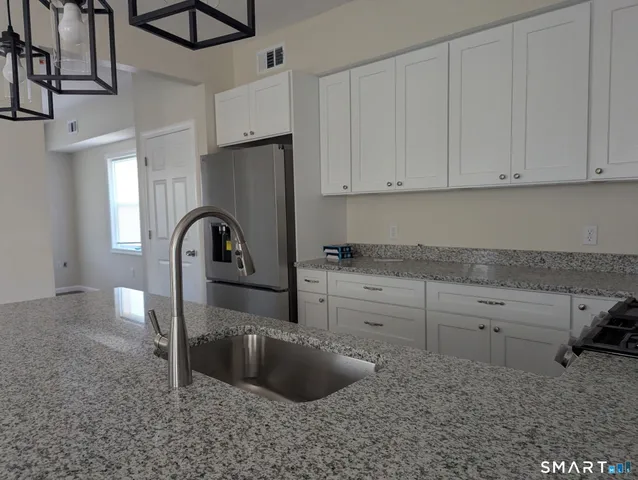 a kitchen with stainless steel appliances granite countertop a sink a stove and a refrigerator