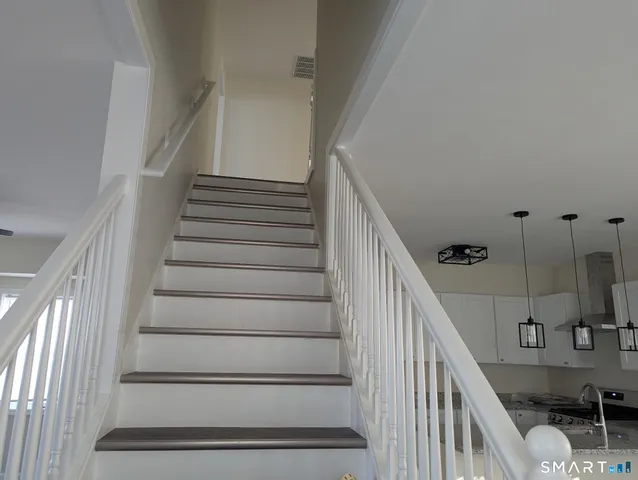 a view of staircase with wooden floor and white walls