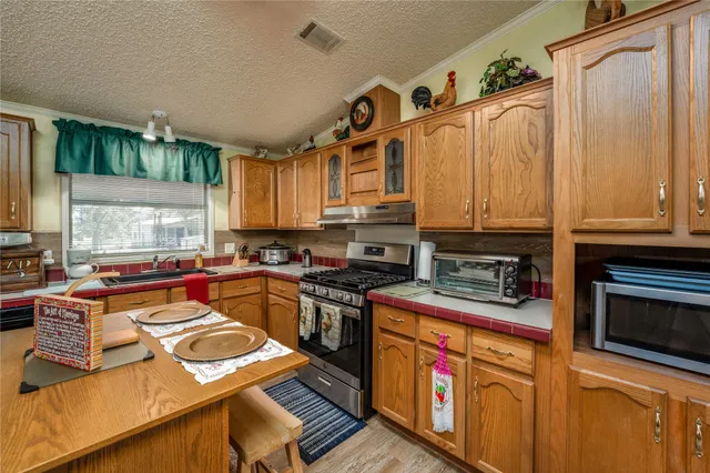 a kitchen with stainless steel appliances granite countertop a stove a sink dishwasher and cabinets with wooden floor