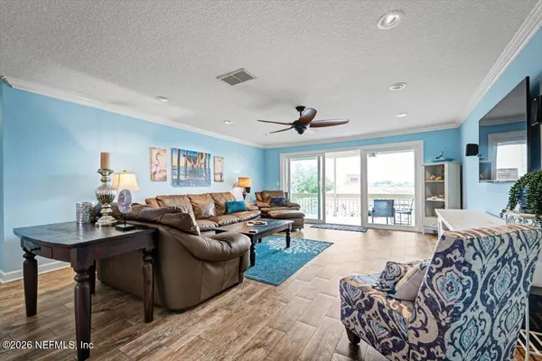 a living room with furniture wooden floor and a ceiling fan