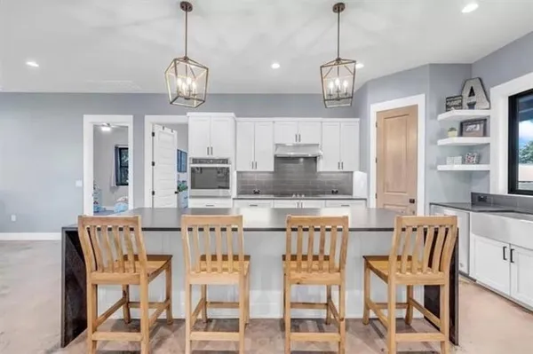 a kitchen with stainless steel appliances kitchen island granite countertop a dining table chairs and white cabinets