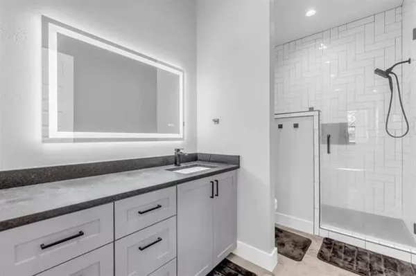 a bathroom with a granite countertop sink a mirror and a shower
