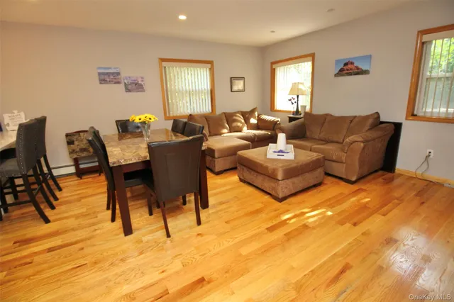 a living room with couches a kitchen island with wooden cabinets and stainless steel appliances