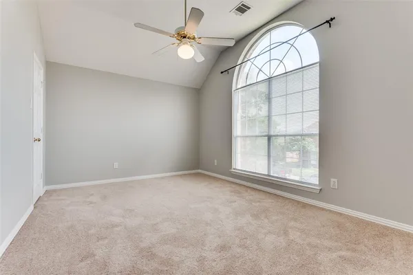 an empty room with a chandelier fan and windows