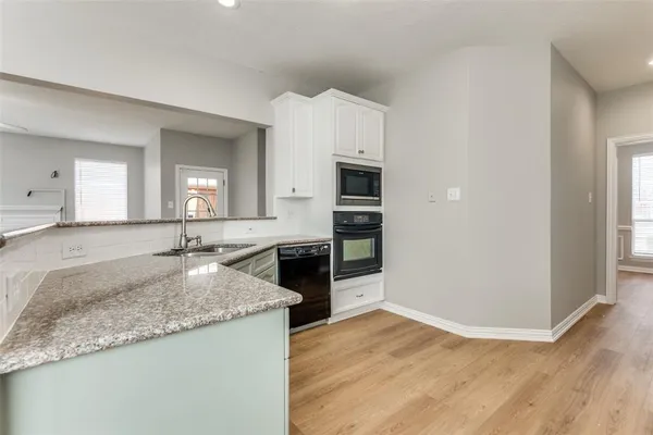 a large kitchen with granite countertop a sink and dishwasher a stove with wooden floor