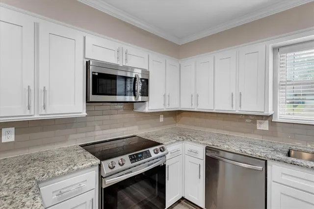 a kitchen with granite countertop white cabinets and stainless steel appliances