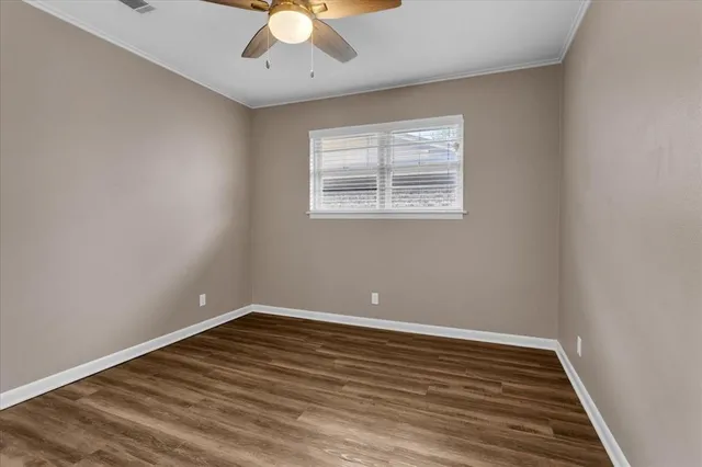 a view of an empty room with wooden floor and a chandelier fan