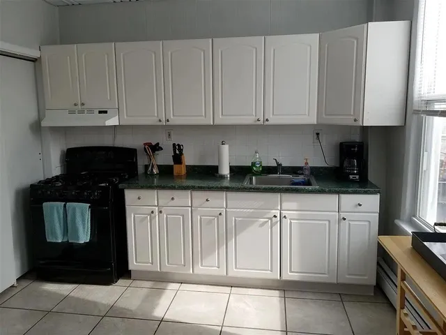 a kitchen with granite countertop white cabinets and stainless steel appliances