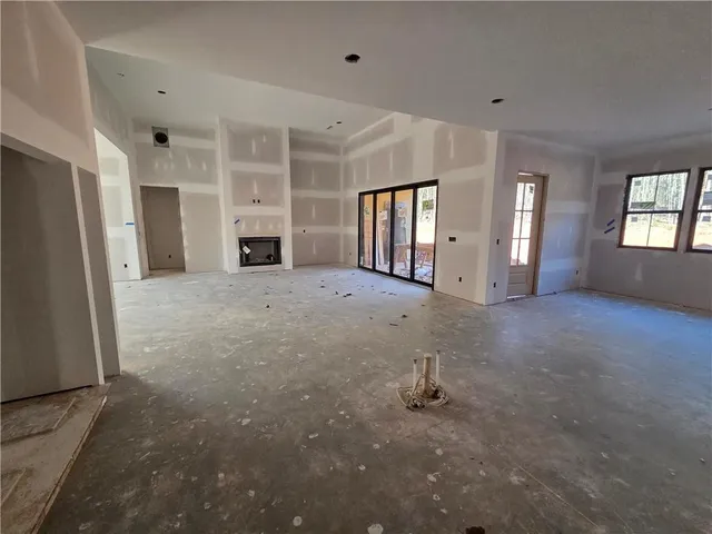 an empty room with windows and fireplace