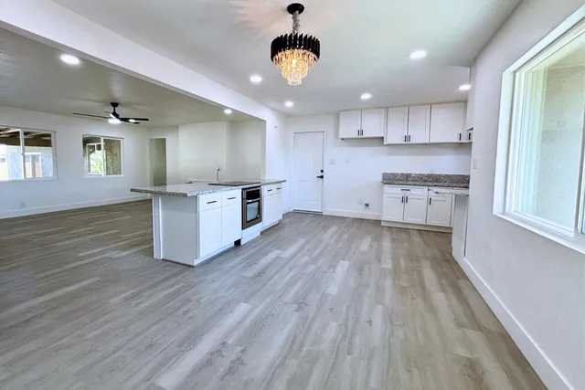 a kitchen with granite countertop a stove a sink dishwasher and a stove with wooden floor