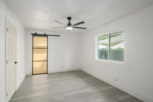 an empty room with windows and fan