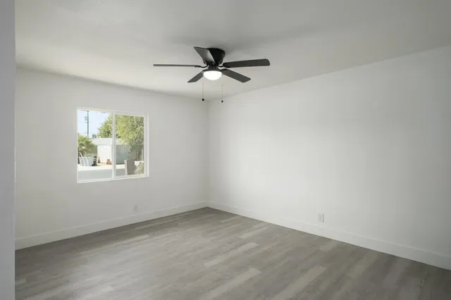 an empty room with a window and a fan
