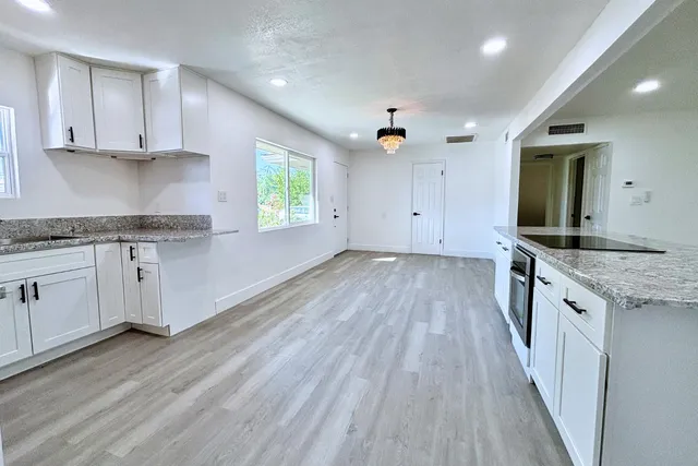 a kitchen with granite countertop wooden floors a stove and white stainless steel appliances