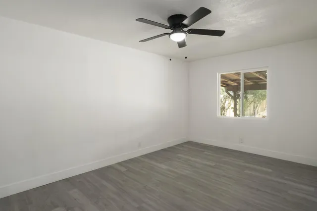 an empty room with a window and a fan