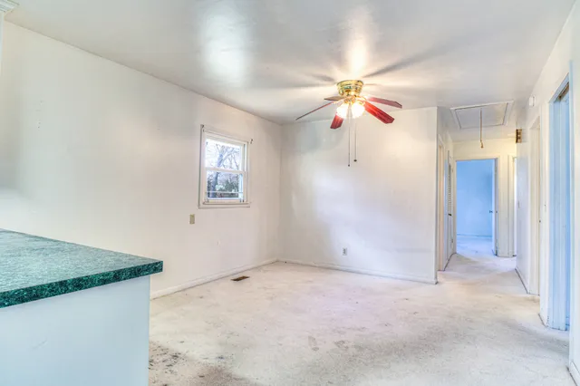 an empty room with windows and chandelier fan