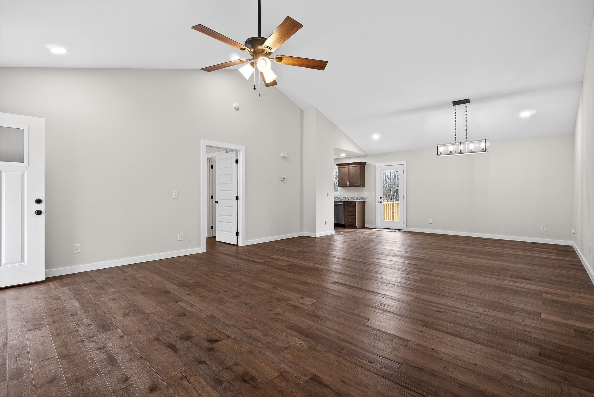 4140 Eller Ridge Road Cookeville, TN 38506 - Photo 22 of 33 an empty room with wooden floor ceiling fan and kitchen view