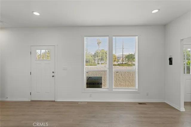 a view of an empty room with wooden floor and a window